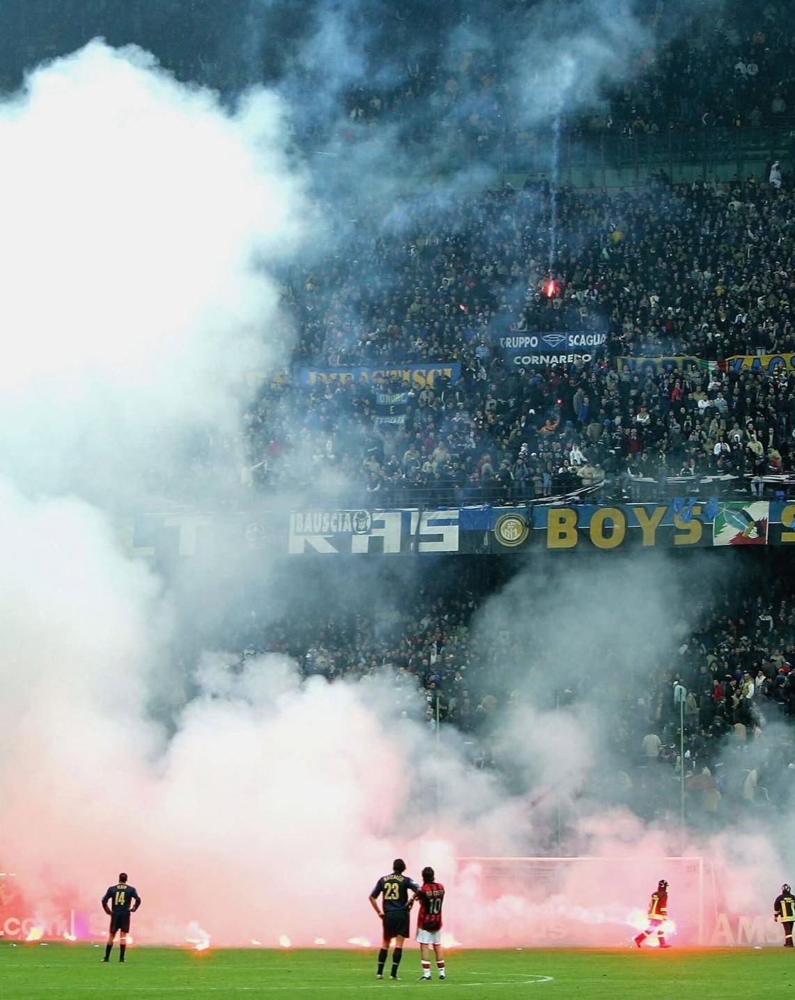 Players on the pitch as flare smoke fills the stands behind them