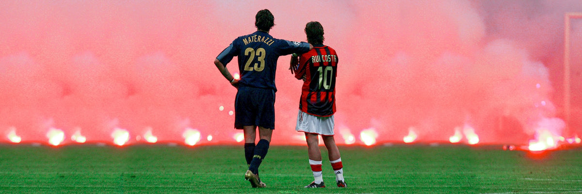 Materazzi and Rui Costa walking off together after the Milan derby, flare smoke behind them